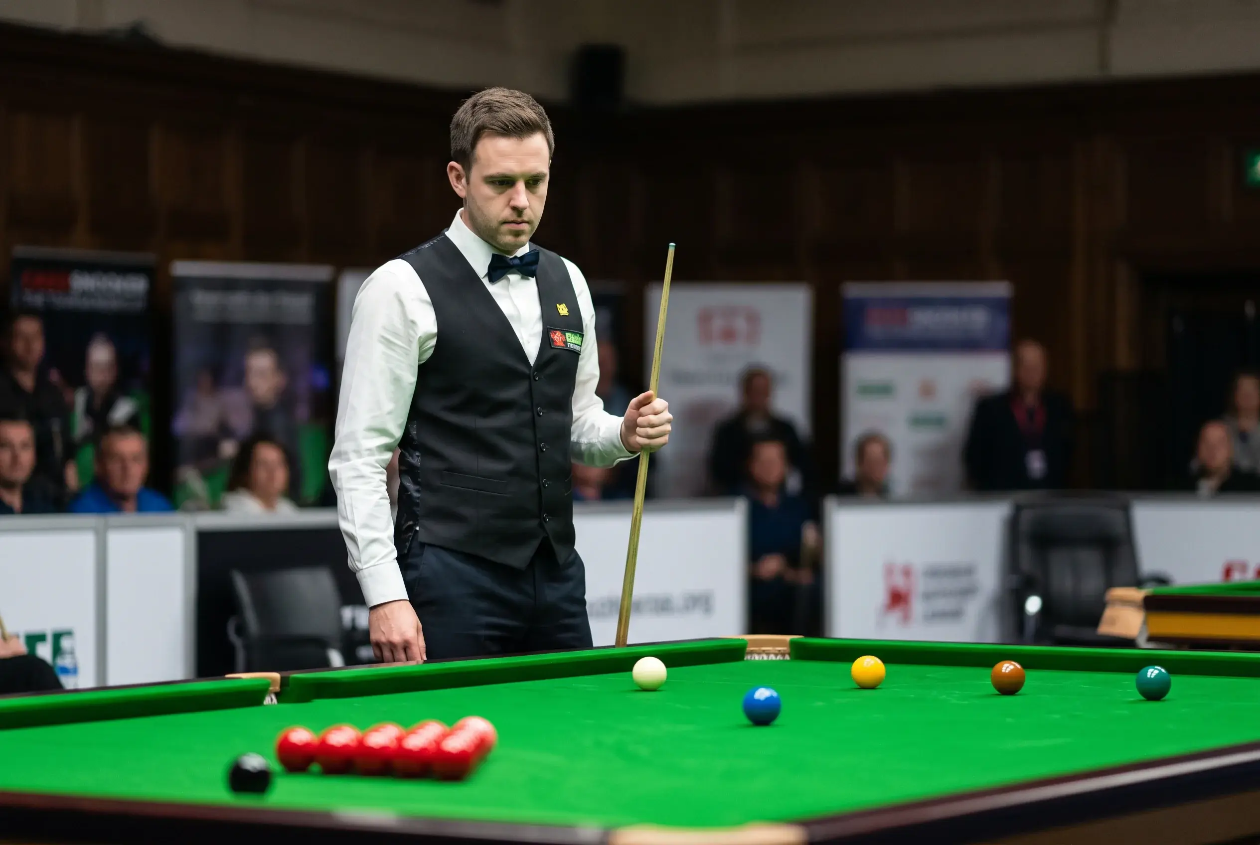 Snookerspieler in Profimontur beim Anvisieren des weißen Balls am Turniertisch