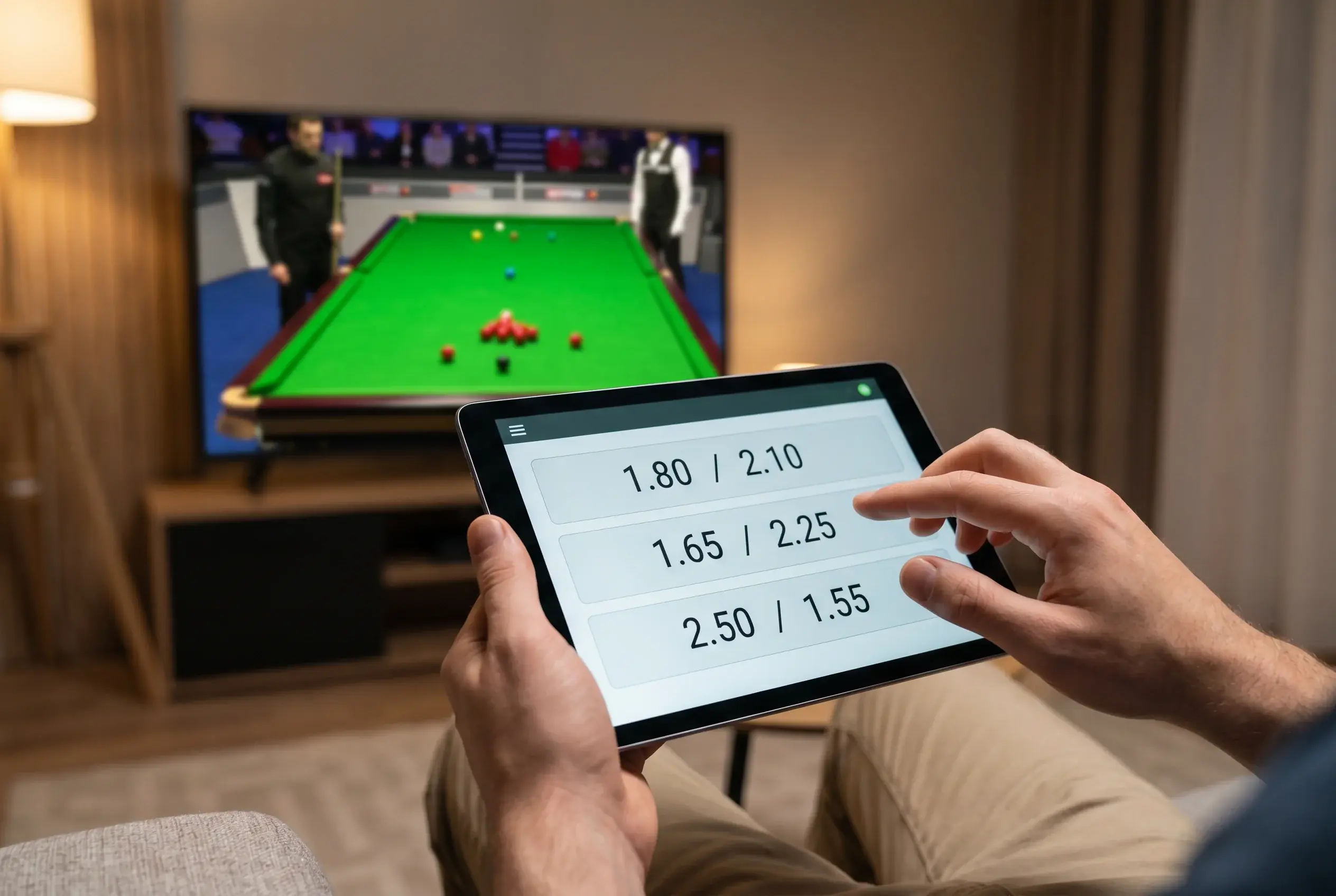 Person prüft Snooker-Wettquoten auf einem Tablet während eines Live-Matches auf dem Fernseher