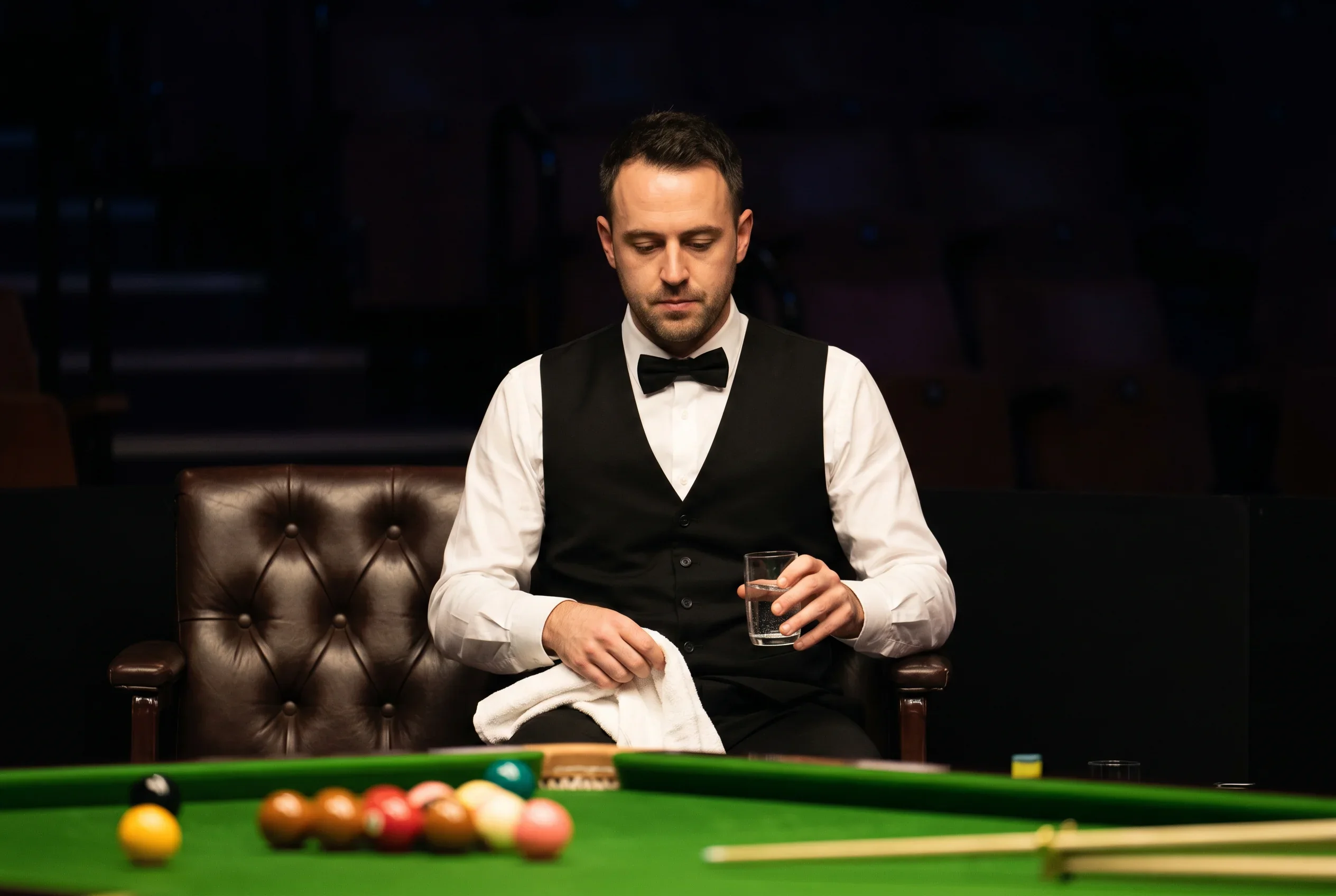 Snookerspieler sitzt während der Session-Pause konzentriert auf seinem Stuhl am Spielfeldrand
