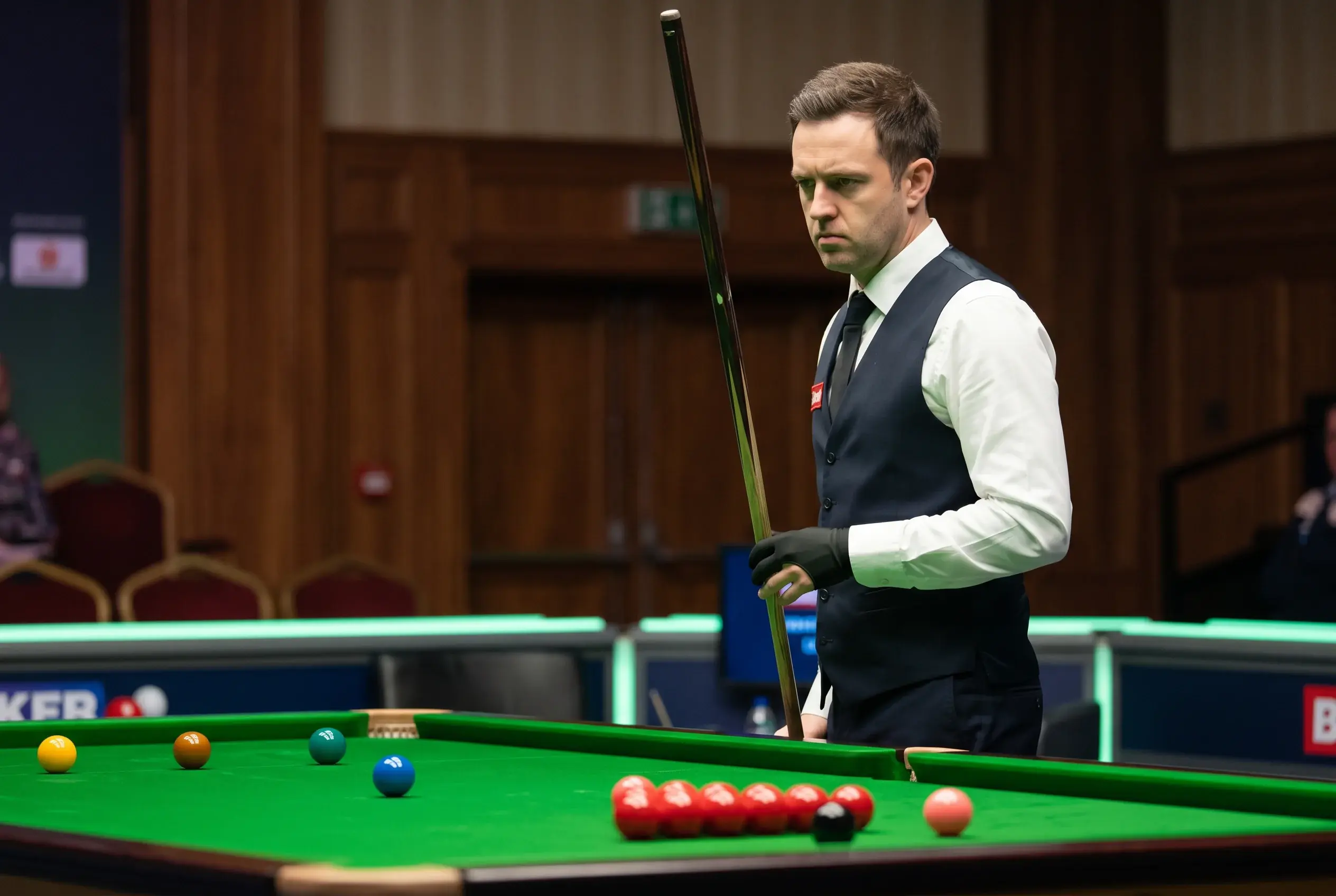 Snookerspieler in Konzentration vor dem Stoß mit Queue am Tisch unter Turnierbeleuchtung