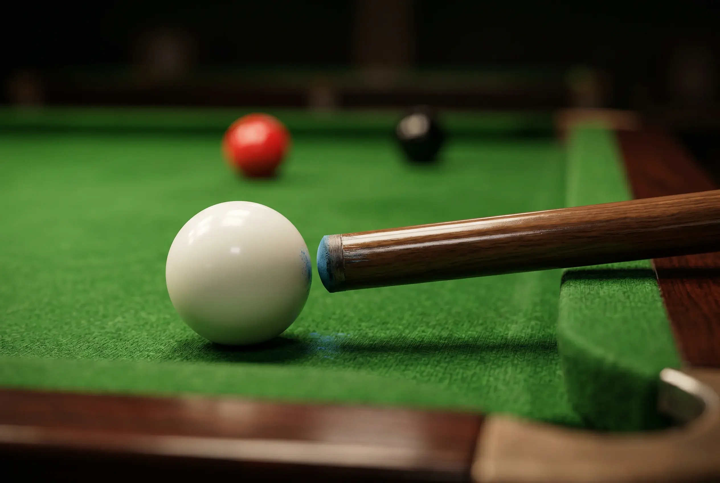 Nahaufnahme eines Queues, der auf die weiße Spielkugel auf dem grünen Tuch eines Snookertisches ausgerichtet ist