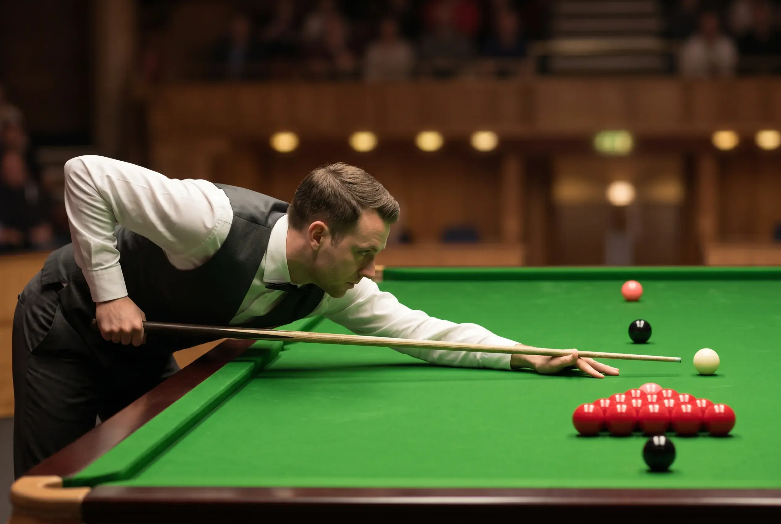 Snookerspieler in weißem Hemd beim präzisen Stoß am Profitisch mit Dreieck und roten Bällen